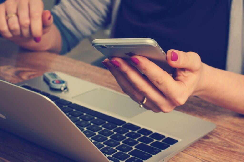 woman working on laptop and phone, view of hands